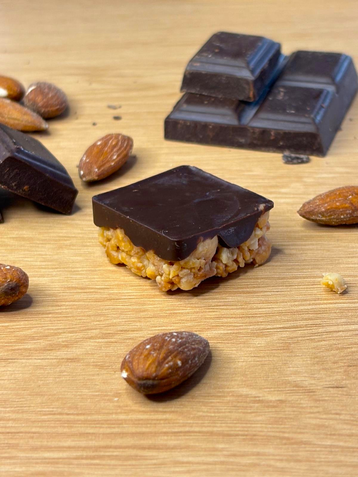 Illustration d'un gâteau Monda aux amandes grillées et au chocolat noir entouré d'amandes et de carreaux de chocolat noir